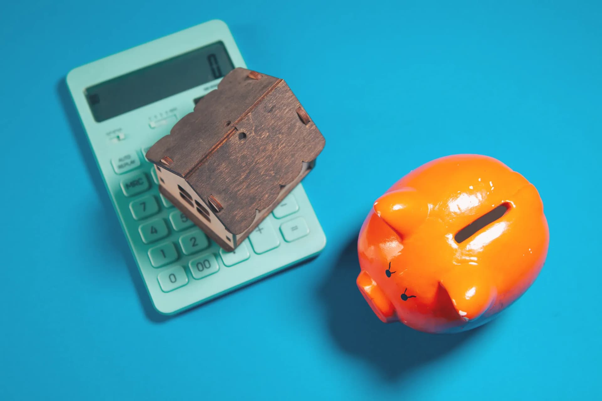 Calculatrice, maquette de maison et tirelire pour estimer le rendement locatif